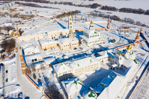 View from drone of Epiphany Staro-Golutvin Monastery with golden domes of cathedrals and tall gate bell tower in Kolomna on winter day, Russia
