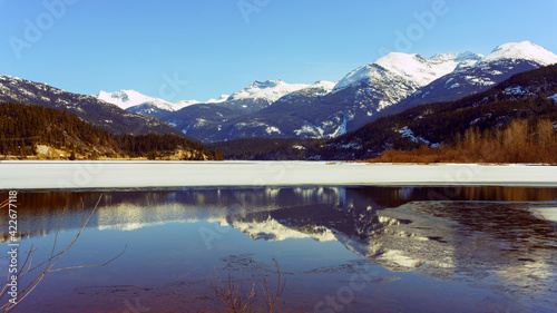 Alpine mountains reflected in pristine BC lake on a sunny pre-spring day © Andrew