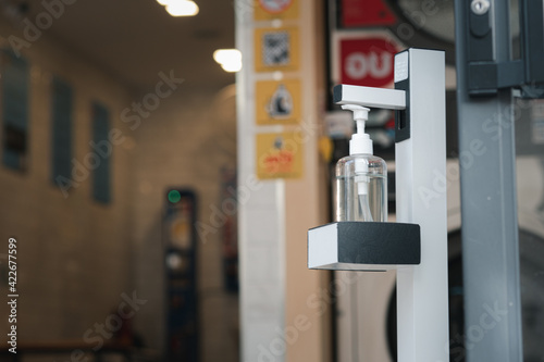 A bottle of alcohol is placed in front of the door for people to use to wash their hands before entering the building.