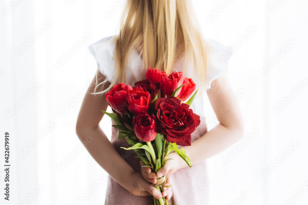 Small girl holding bouquet of red tulip flowers. Concept for greeting card