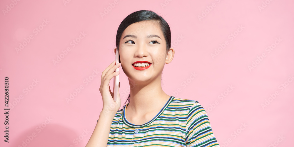 Laughing woman talking on the phone isolated on a pink background Laughing woman talking on the phone isolated on a pink background