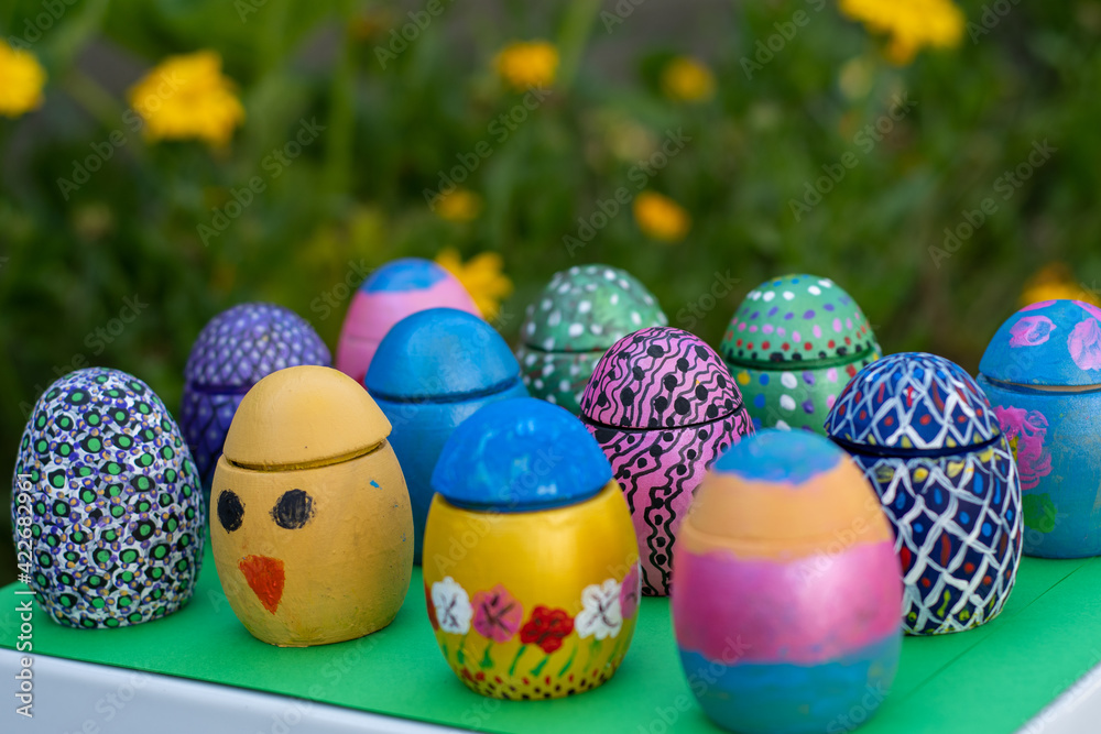 Hand-made Easter eggs on a green pedastal in front of yellow and orange spring flowers Hand-made Easter eggs on a green pedastal in front of yellow and orange spring flowers
