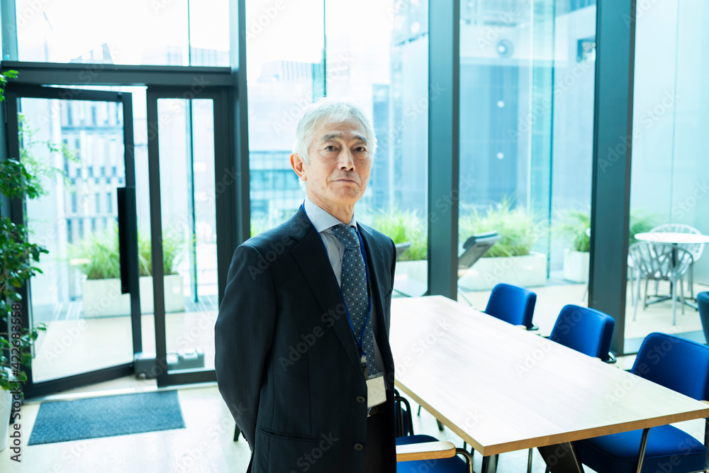 エントランスの前にたつベテランの男性社員 Stock Photo | Adobe Stock