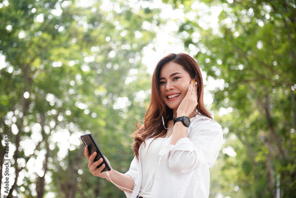 Thai women of Asian descent use a smartphone on the street on a sunny summer day. Thai women of Asian descent use a smartphone on the street on a sunny summer day.