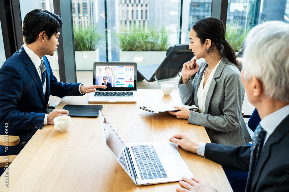都心の企業で働くビジネスチームがオンライン会議を行っている