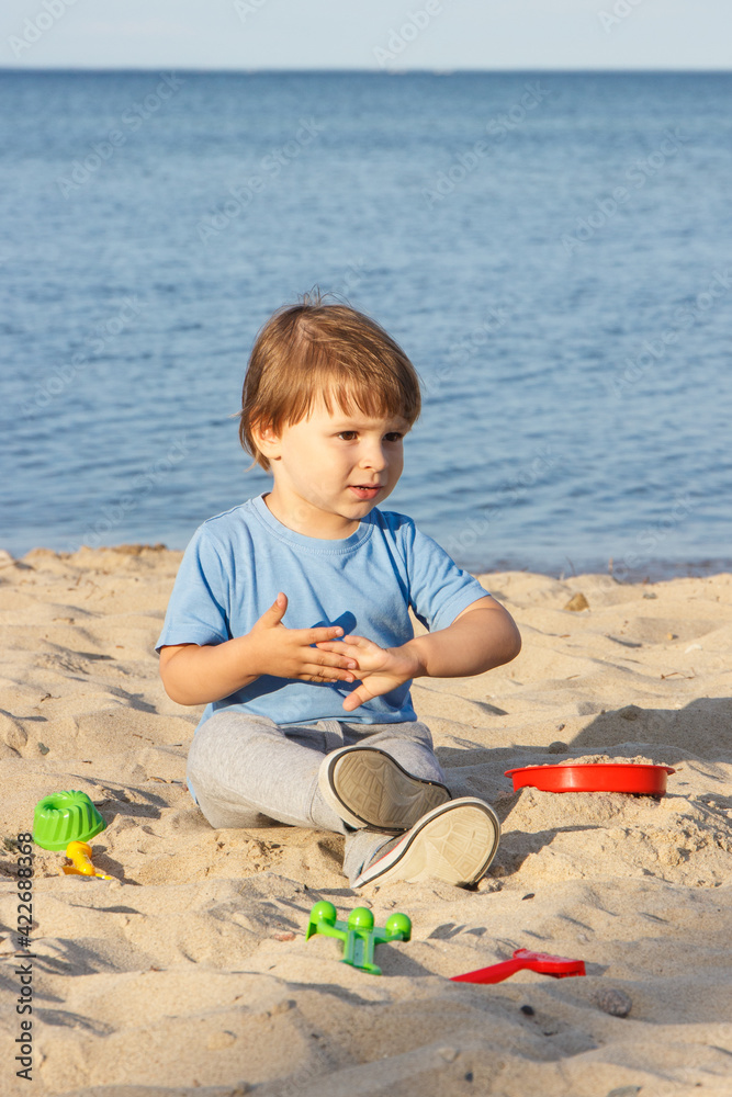 Smiling boy playing on sand at beach. Summer, vacation and relaxation time concept Smiling boy playing on sand at beach. Summer, vacation and relaxation time concept