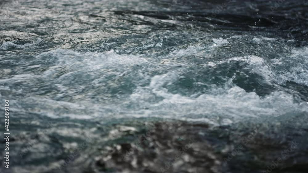 River water flowing in mountain river. Rapid water stream in slow motion River water flowing in mountain river. Rapid water stream in slow motion