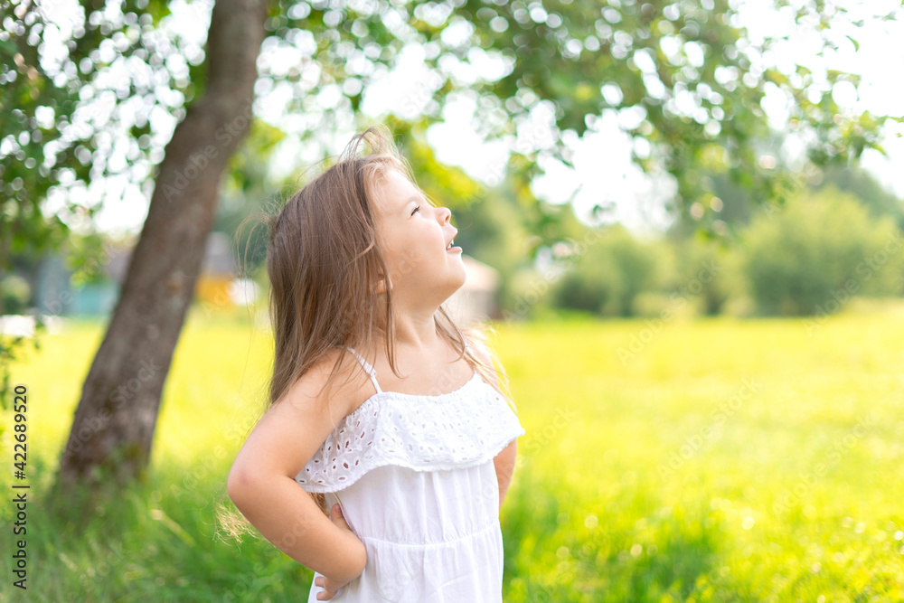 child girl with long hair in a white dress rejoices in the sun on a summer day child girl with long hair in a white dress rejoices in the sun on a summer day