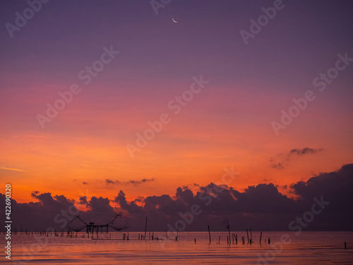 Silhouette photo of fisherman trap fish in front of sunrise scene at famous Pak Pra Phatthalung provience Thailand photo