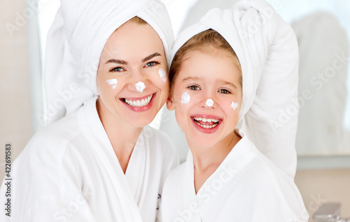 Happy woman and girl with face cream after shower