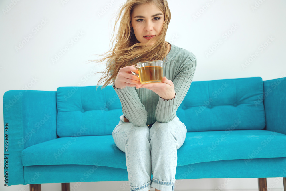 Young woman sitting at home and drinking tea, interior. High quality photo.