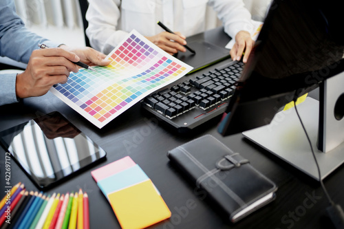 Freelance creative designer team creation project with color chart in meeting.