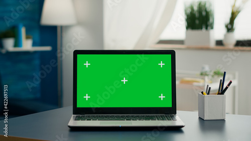 Laptop computer with mock up green screen chroma key standing on home office desk with nobody in it. Professional set up is ready for e commmerce courses using isolated pc