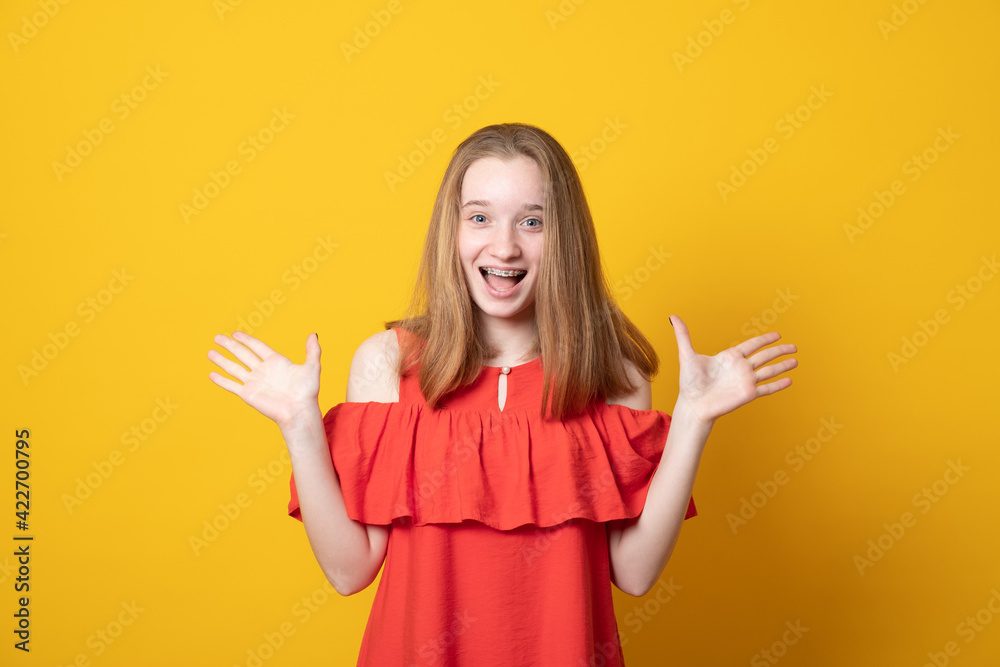Happy girl raises palms from joy, happy to receive awesome present from someone, shouts loudly. Excited teen girl yells. Happy girl raises palms from joy, happy to receive awesome present from someone, shouts loudly. Excited teen girl yells.