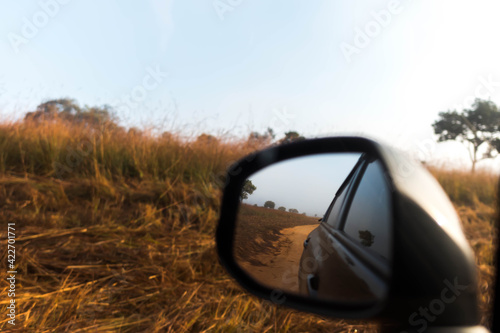 grass field reflection image at wing mirror of car in travel