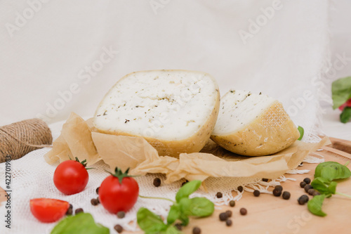 Medium hard cheese head parmesan on wooden board, with cheese parmesan with tomatoes on the table