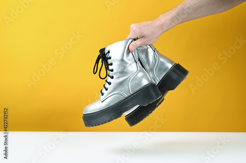 Silver shoes in hand  on a yellow background