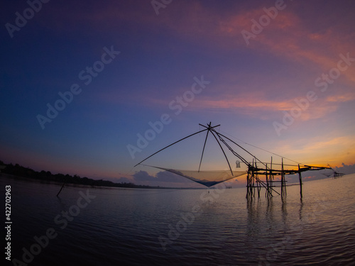 Silhouette photo of fisherman trap fish in front of sunrise scene at famous Pak Pra Phatthalung provience Thailand