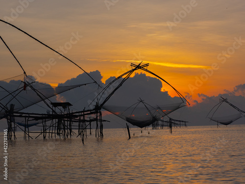 Silhouette photo of fisherman trap fish in front of sunrise scene at famous Pak Pra Phatthalung provience Thailand photo