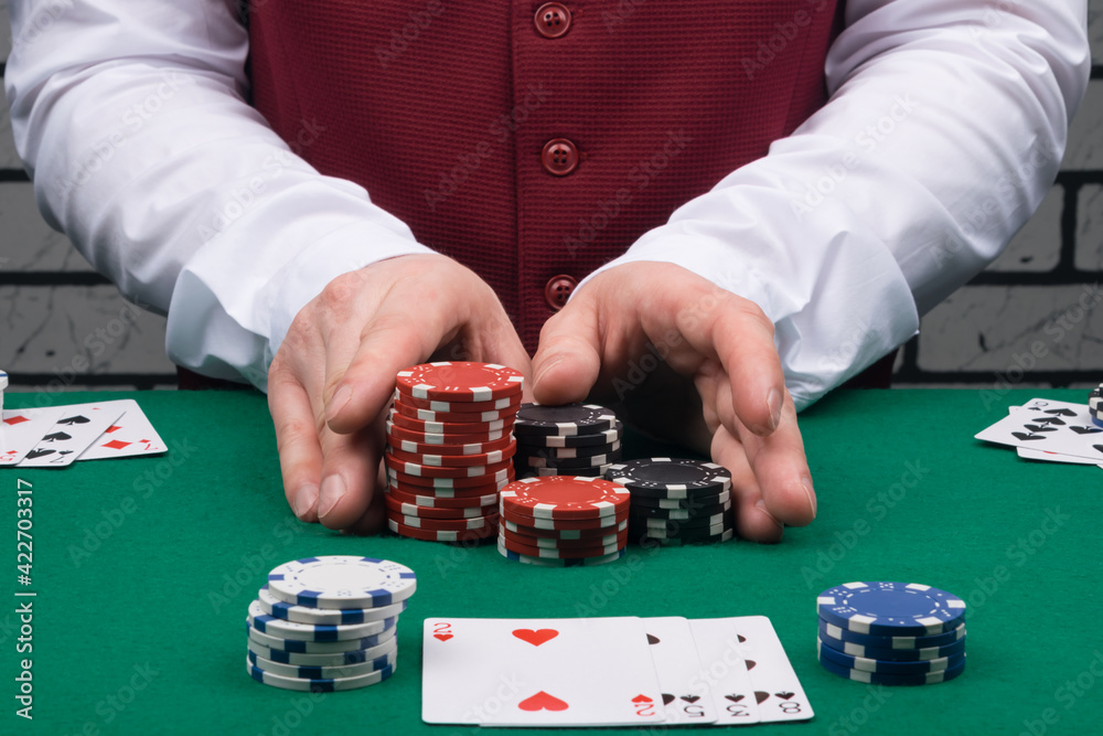 the croupier in the casino, at the green table, gives a big win with chips to the player with the cards opposite the croupier in the casino, at the green table, gives a big win with chips to the player with the cards opposite