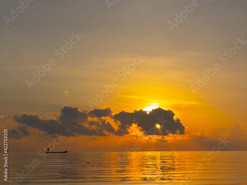 Amazing time of silhouette image of Thai fishermen are fishing on small traditional fishing boat when sunrise with golden sky