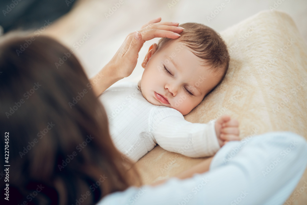Mom gently touching sleeping little child Mom gently touching sleeping little child