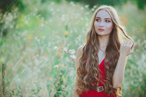 Young beautiful girl in a red dress in nature