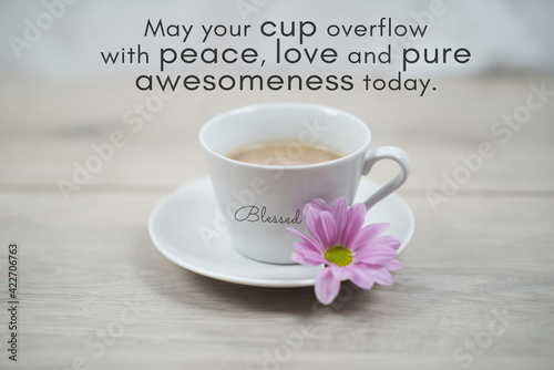 Inspirational quote - May your cup overflow with peace, love and pure awesomeness today. Blessed. 
With cup of morning coffee and purple flower on soft white table background. photo