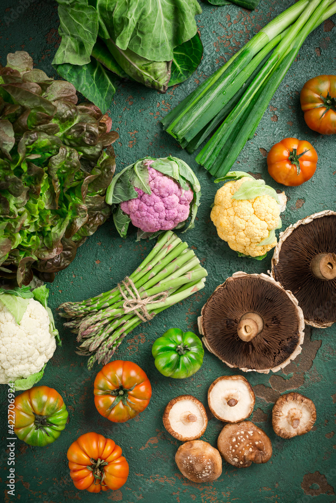 Assortment of organic vegetables and edible mushrooms on green background