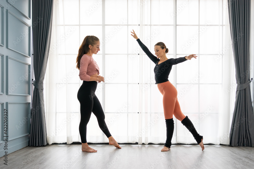 Fototapeta premium Female ballet teachers training ballerina to have right postures in the private class at home studio. Choreographer teaching caucasian dancers to movements of modern music. Concept of dance rehearsal