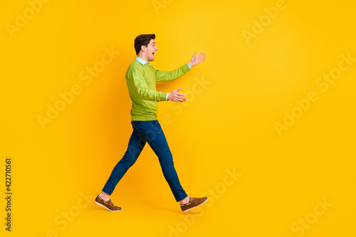 Full length body size profile side view of nice cheerful guy walking meeting hugging invisible friend isolated over bright yellow color background