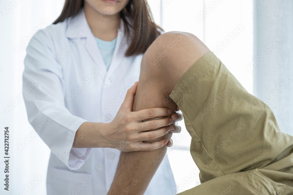 Female doctor hands doing physical therapy By extending the leg and knee of a male patient Female doctor hands doing physical therapy By extending the leg and knee of a male patient