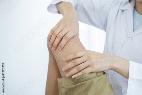 Female doctor hands doing physical therapy By extending the leg and knee of a male patient