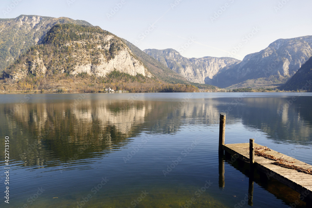 Wooden pier by Lake Hallstatt in Austria with reflection of the mountains