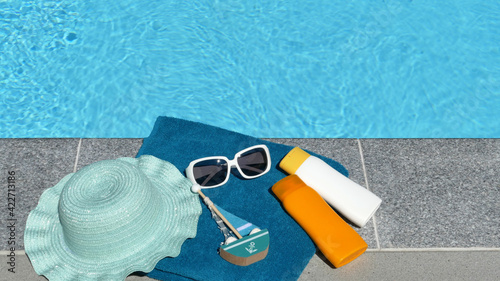 Sonnencreme Handtuch und Sonnenbrille am Pool