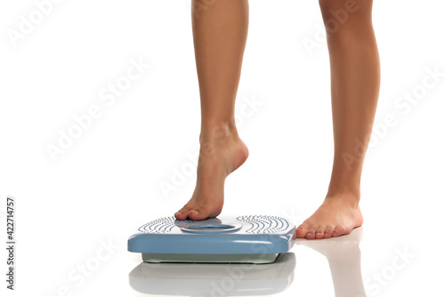 Female legs steps on a scales
