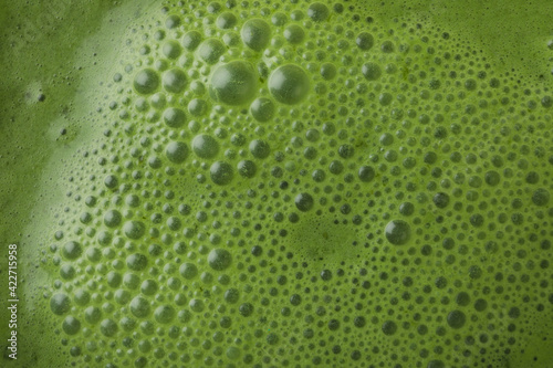 Fresh green smoothie on whole background, close up