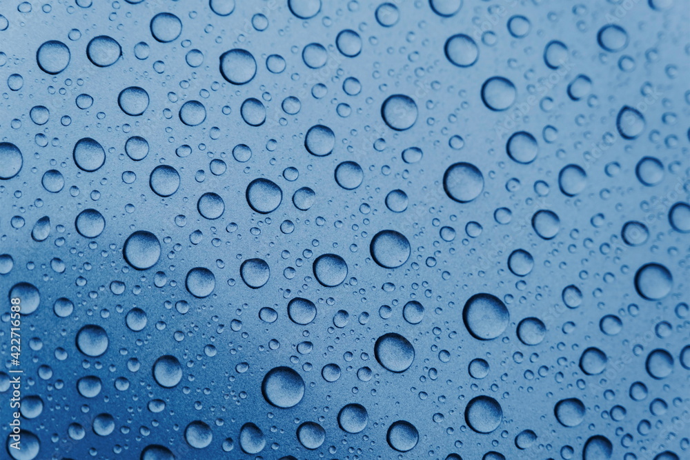 Close-up of water droplets and drops on a blue surface. Texture and structure after rain. Ecology.