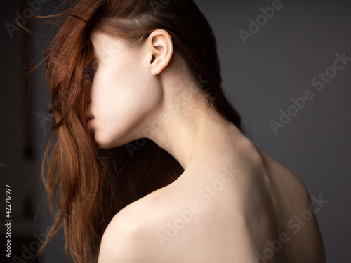 Sexy woman with a naked back on a gray background red hair back view