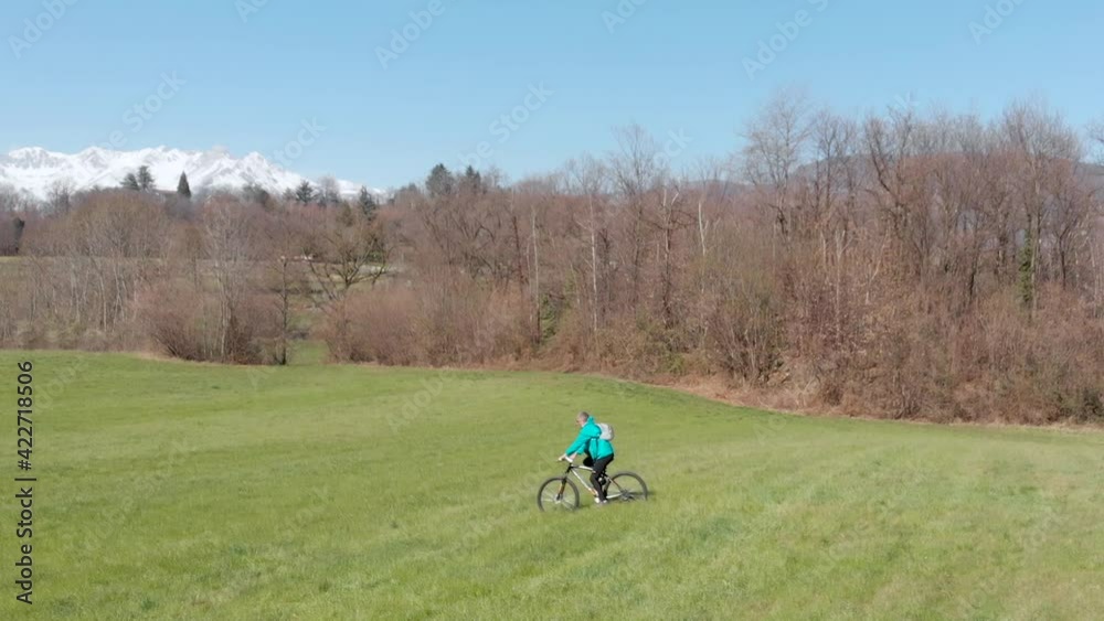 Aerial slow motion: man having fun by riding mountain bike in the grass on sunny day, scenic alpine landscape, fitness wellbeing sport in nature Aerial slow motion: man having fun by riding mountain bike in the grass on sunny day, scenic alpine landscape, fitness wellbeing sport in nature