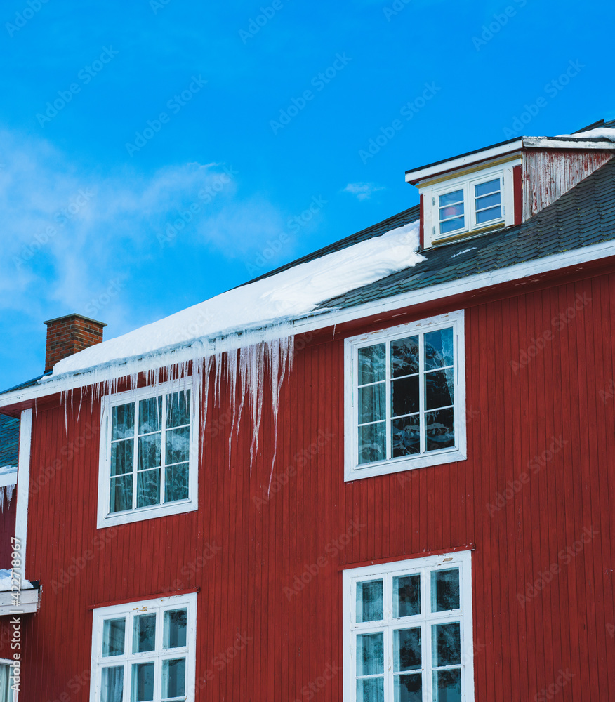 Long and massive icicles hanging from the roof of an old building. 