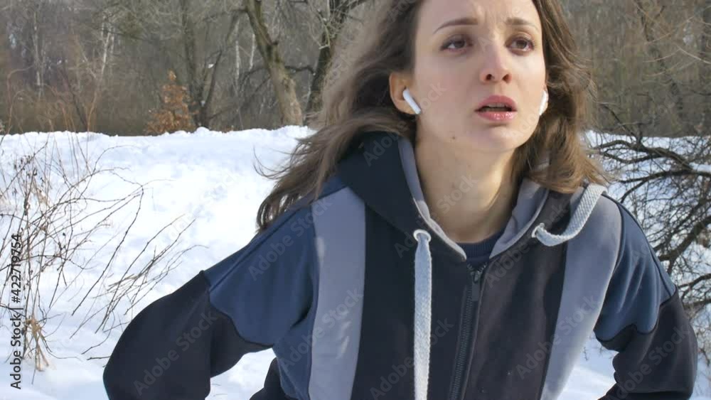 Spring or winter portrait of young athletic girl running in the park in dark sportwear on trees with snow background. Healthy lifestyle concept. Spring or winter portrait of young athletic girl running in the park in dark sportwear on trees with snow background. Healthy lifestyle concept.