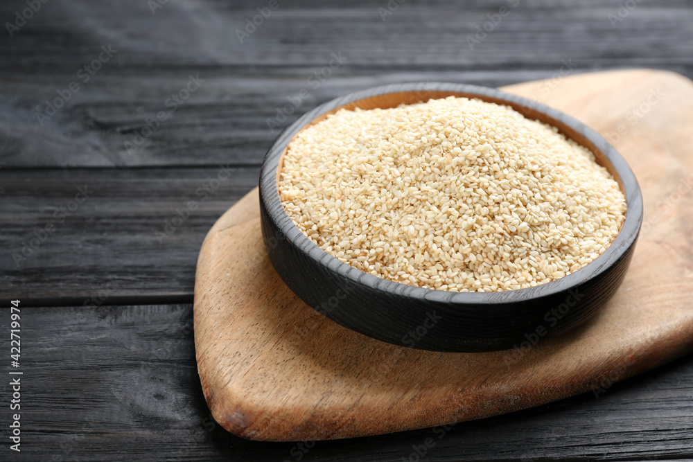 Plate with sesame seeds on black wooden table Plate with sesame seeds on black wooden table
