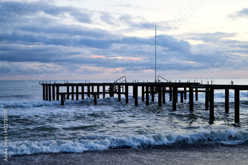 View from beach to water of sea  waves with white foam  pierce and sky with clouds in a nice evening.