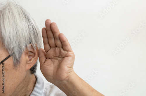 Asian senior woman having impaired hearing,deaf,ear disease,old elderly people trying to listening with hand over her ear,trouble hearing,chronic otitis,acute ear infections,problems of deafness