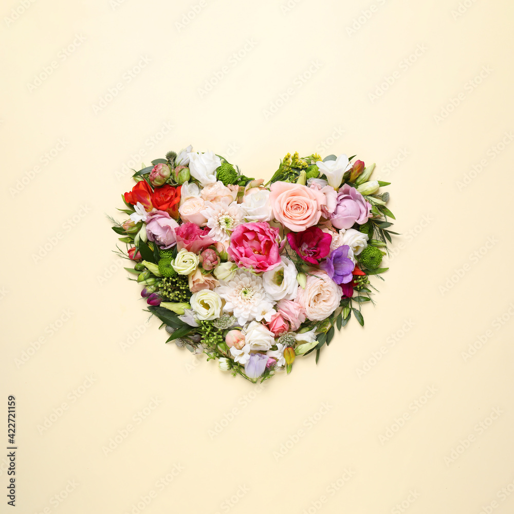 Beautiful heart made of different flowers on beige background, top view Beautiful heart made of different flowers on beige background, top view