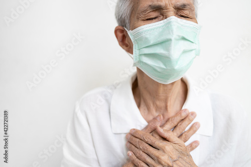Asian senior grandmother suffering from pain in chest with acute dyspnea or asthma disease,Tired old elderly eyes closed and hand touch her chest,difficulty breathing,shortness of breath,breathless