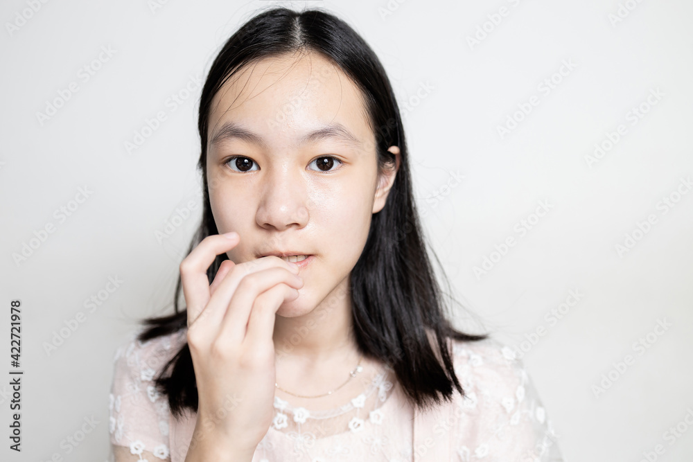 Worried asian teen girl bites fingernails,risk of germs,bacterial disease,Coronavirus into the body from dirty fingers,hand on mouth biting her nails,mental health problems,psychiatric,hygiene concept Worried asian teen girl bites fingernails,risk of germs,bacterial disease,Coronavirus into the body from dirty fingers,hand on mouth biting her nails,mental health problems,psychiatric,hygiene concept