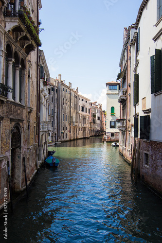 Beautiful narrow canal with gondolas and small boats and historical buildings in Venice  Italy