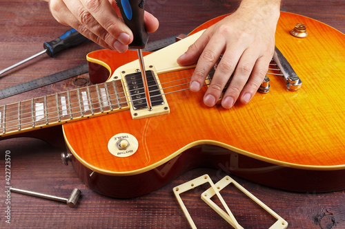 Fotografie Guitar technician tune the height pickups on electric guitar at workplace